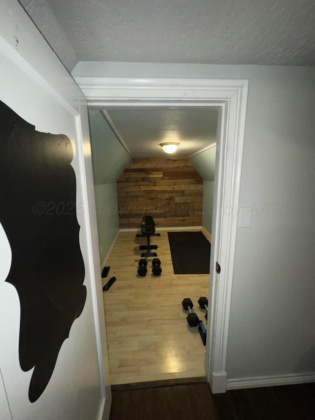 detailed view of wooden walls, wood finished floors, a textured ceiling, and baseboards