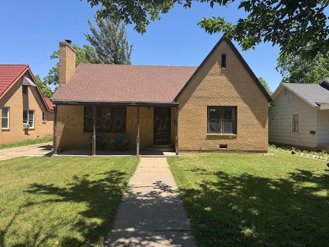 tudor house featuring brick siding, a chimney, and a front yard