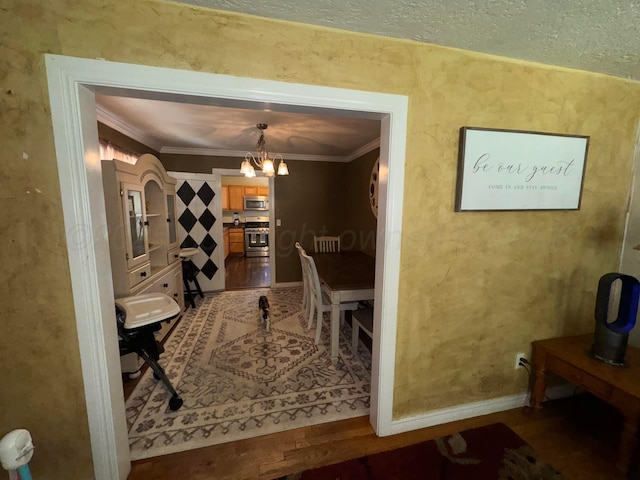 dining area with ornamental molding, a chandelier, baseboards, and a textured ceiling
