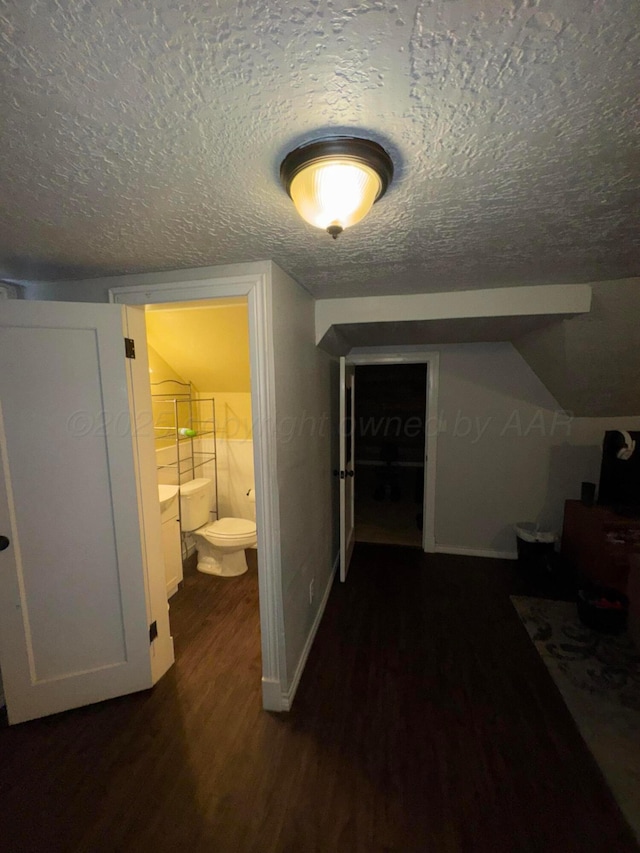 hall featuring dark wood-style floors, a textured ceiling, and baseboards
