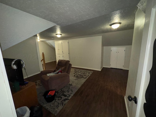 living room with a textured ceiling, dark wood-style flooring, and baseboards