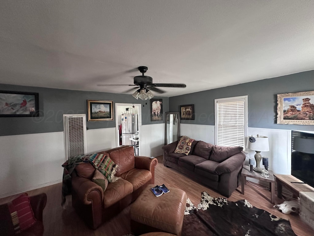 607 N El Paso Ave, Tulia, TX 79088 - living room featuring a wainscoted wall, ceiling fan, and wood finished floors
