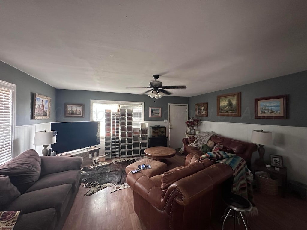 607 N El Paso Ave, Tulia, TX 79088 - living area featuring wood finished floors, plenty of natural light, ceiling fan, and a wainscoted wall
