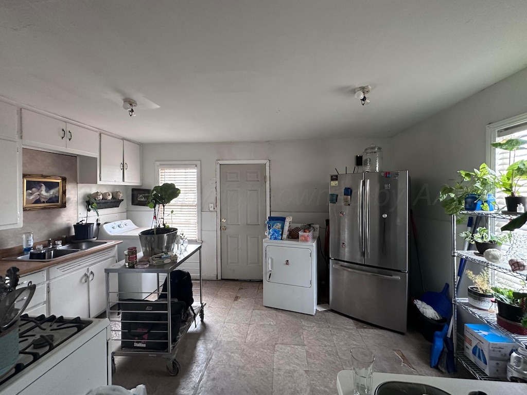 607 N El Paso Ave, Tulia, TX 79088 - kitchen featuring freestanding refrigerator, washer / dryer, plenty of natural light, and white cabinetry