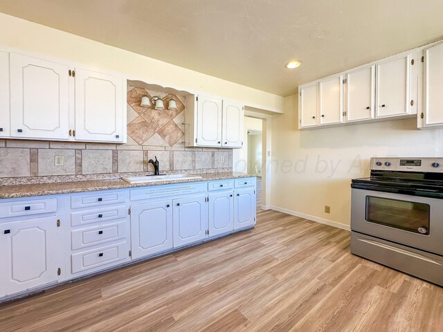 kitchen with baseboards, white cabinets, stainless steel electric stove, a sink, and light wood-style flooring