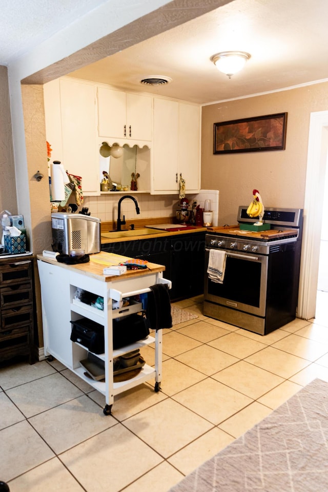 1611 S Palo Duro St, Amarillo, TX 79106 - kitchen featuring gas stove, light tile patterned flooring, decorative backsplash, white cabinetry, and dark cabinetry