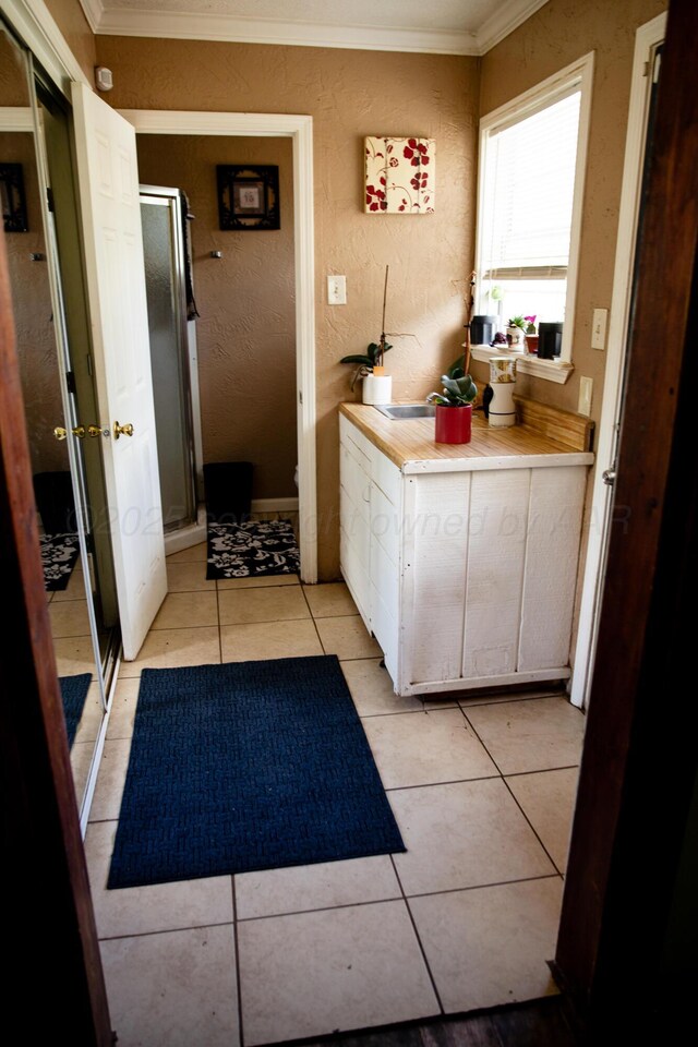 1611 S Palo Duro St, Amarillo, TX 79106 - full bathroom with crown molding, a stall shower, a textured wall, and tile patterned flooring