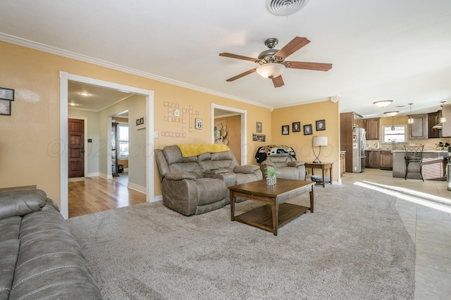 living room with ceiling fan, ornamental molding, and light tile patterned floors