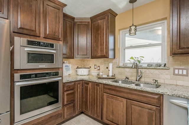kitchen with sink, appliances with stainless steel finishes, backsplash, light stone countertops, and light tile patterned flooring