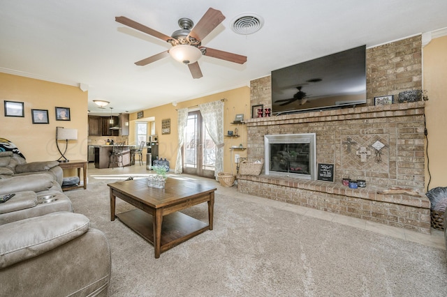 living room featuring a brick fireplace, light colored carpet, ornamental molding, and ceiling fan