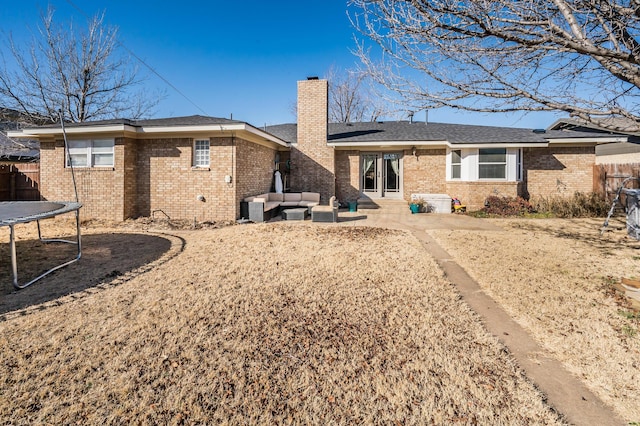 rear view of property with an outdoor living space, a trampoline, and a patio area