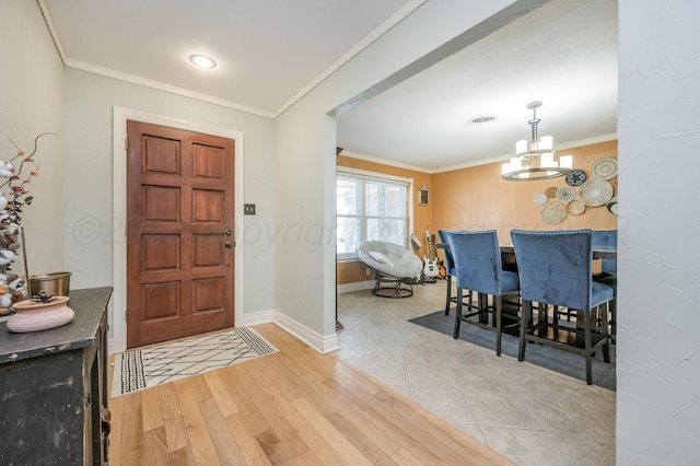 entrance foyer featuring an inviting chandelier, crown molding, and light wood-type flooring
