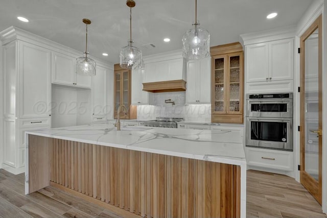 kitchen with tasteful backsplash, white cabinetry, custom range hood, a sink, and stainless steel double oven