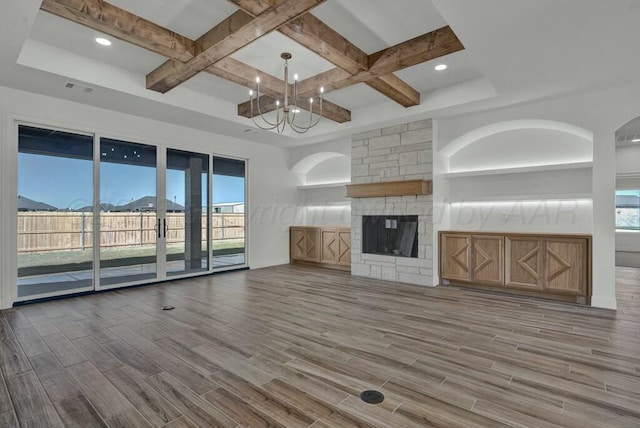 unfurnished living room with beamed ceiling, coffered ceiling, wood finished floors, and a fireplace