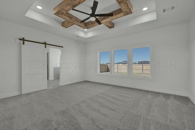 unfurnished bedroom with visible vents, carpet floors, a barn door, a raised ceiling, and baseboards