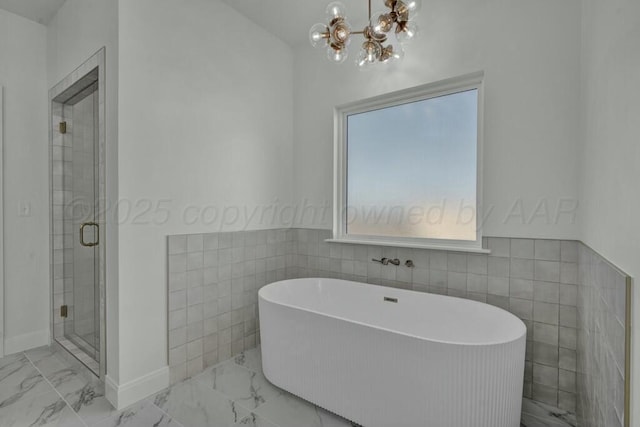 full bathroom with a freestanding tub, marble finish floor, and tile walls
