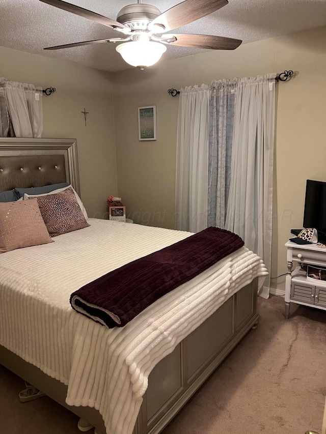 carpeted bedroom featuring a ceiling fan and a textured ceiling