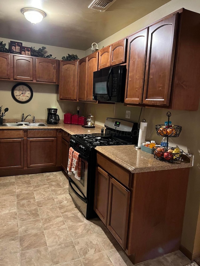 kitchen featuring black microwave, a sink, visible vents, light countertops, and range with gas cooktop