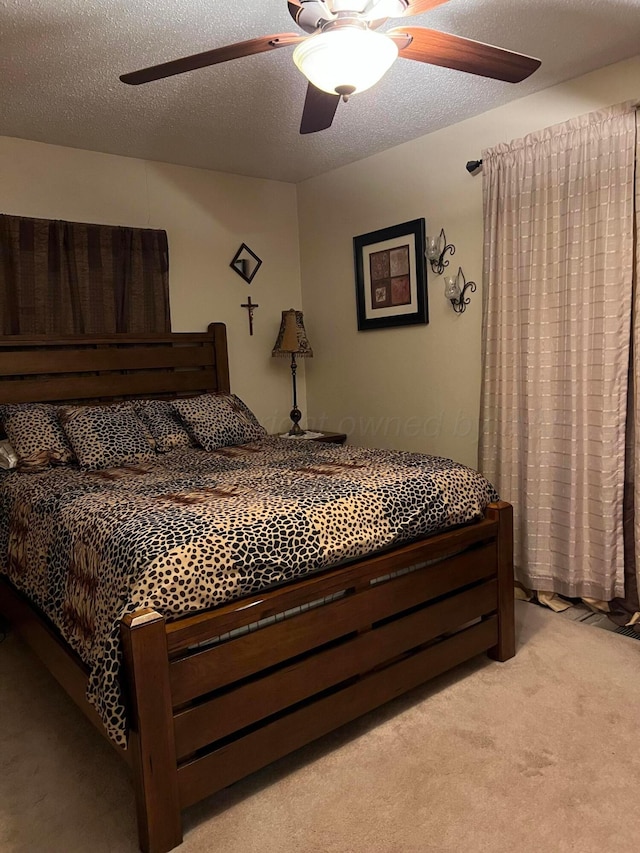 bedroom with a textured ceiling, light carpet, and a ceiling fan