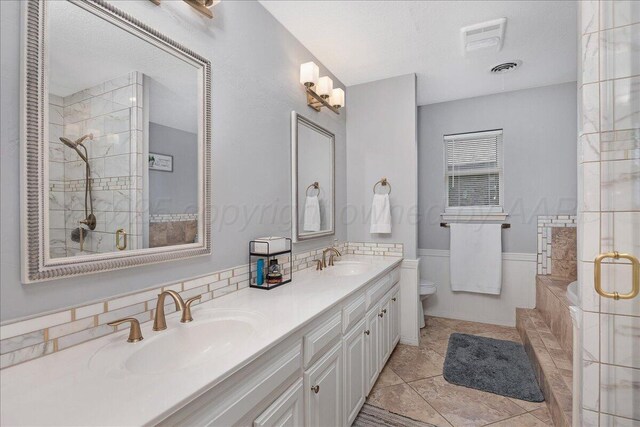 4022 Pinehurst Dr, Amarillo, TX 79109 - full bathroom featuring toilet, tiled shower, double vanity, a garden tub, and wainscoting