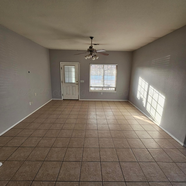 tiled empty room featuring ceiling fan