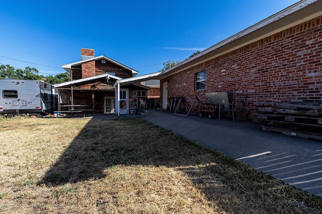 1207 Lee St, Borger, TX 79007 - rear view of property with a chimney, a yard, and brick siding