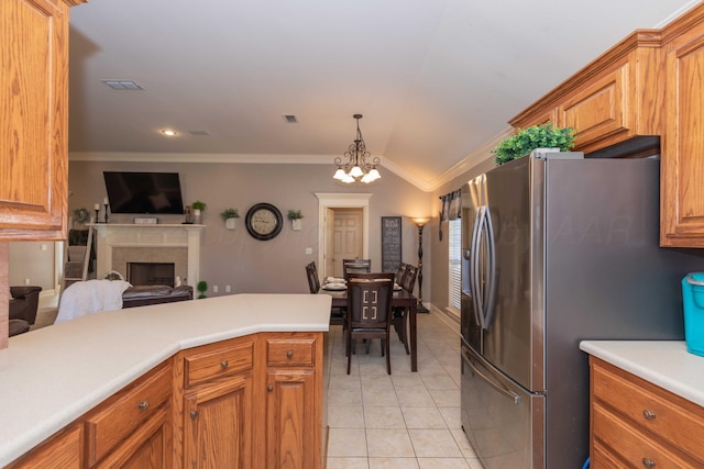 kitchen with brown cabinets, visible vents, ornamental molding, a fireplace, and stainless steel fridge