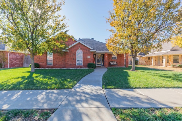 ranch-style house with a shingled roof, brick siding, and a front yard
