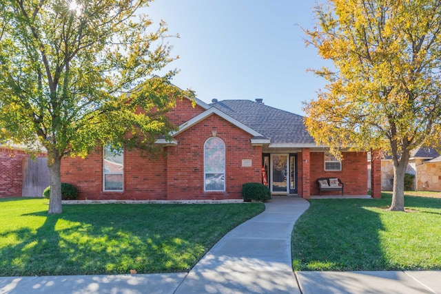 view of front facade featuring brick siding, a shingled roof, and a front yard
