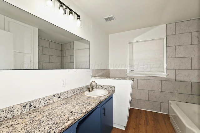 1603 SW 35th Ave, Amarillo, TX 79109 - full bathroom featuring vanity, wood finished floors, a tub, and tile walls