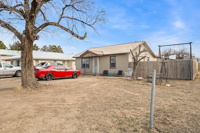 view of front facade featuring metal roof, fence, and stucco siding