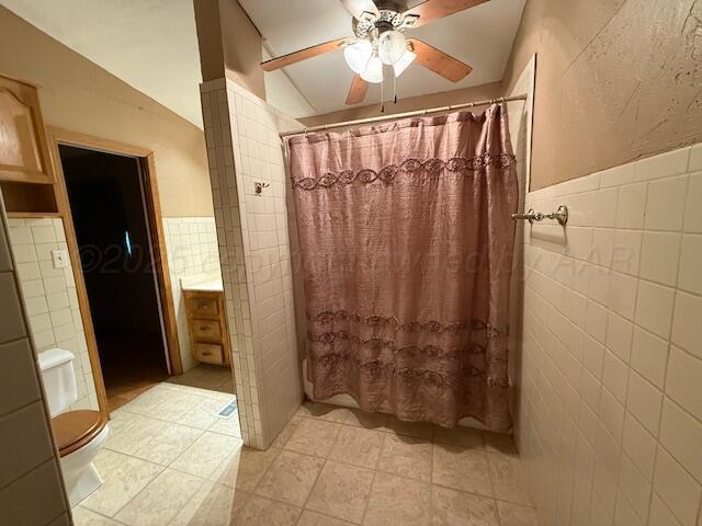 407 N Powell St, Pampa, TX 79065 - bathroom featuring a shower with curtain, toilet, tile walls, and a ceiling fan