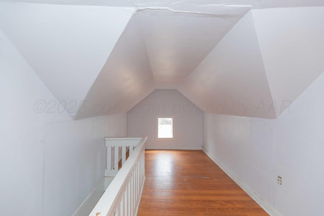 additional living space with hardwood / wood-style flooring and vaulted ceiling