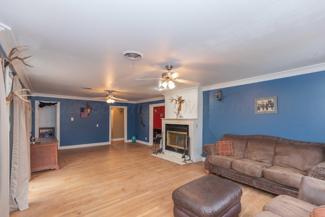 living room with crown molding, ceiling fan, and light wood-type flooring