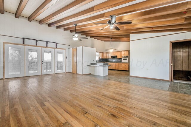 unfurnished living room featuring beam ceiling, french doors, and light wood-type flooring