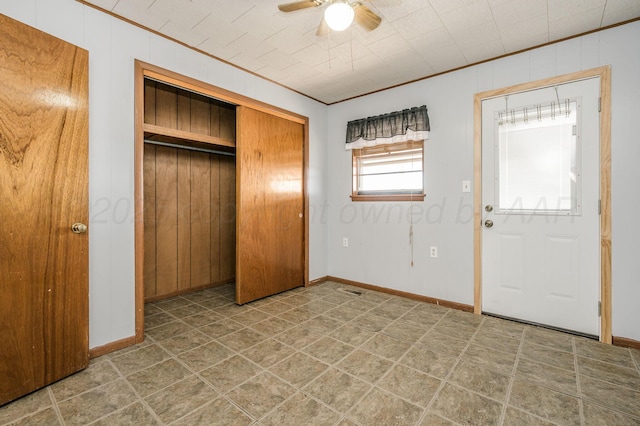 foyer entrance with ornamental molding and ceiling fan