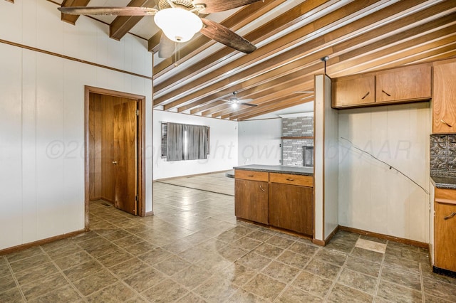 kitchen with ceiling fan, wooden walls, and vaulted ceiling with beams