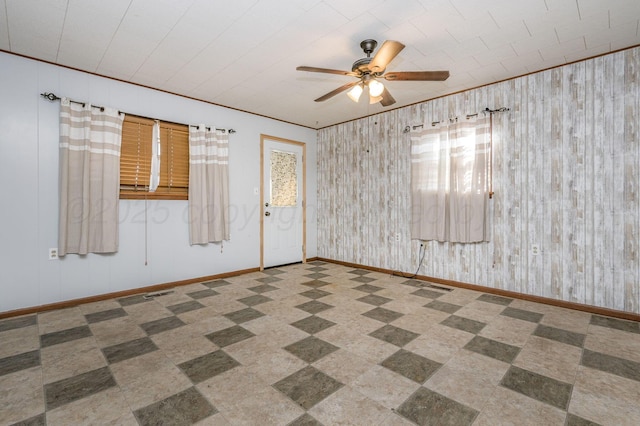 spare room with crown molding, wooden walls, and ceiling fan