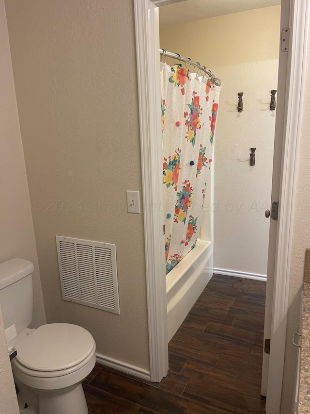 bathroom featuring hardwood / wood-style flooring, shower / tub combo with curtain, and toilet
