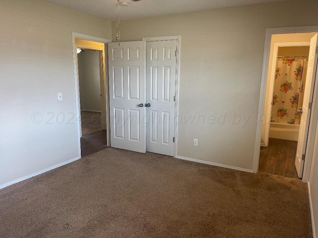 unfurnished bedroom with ensuite bathroom and carpet floors