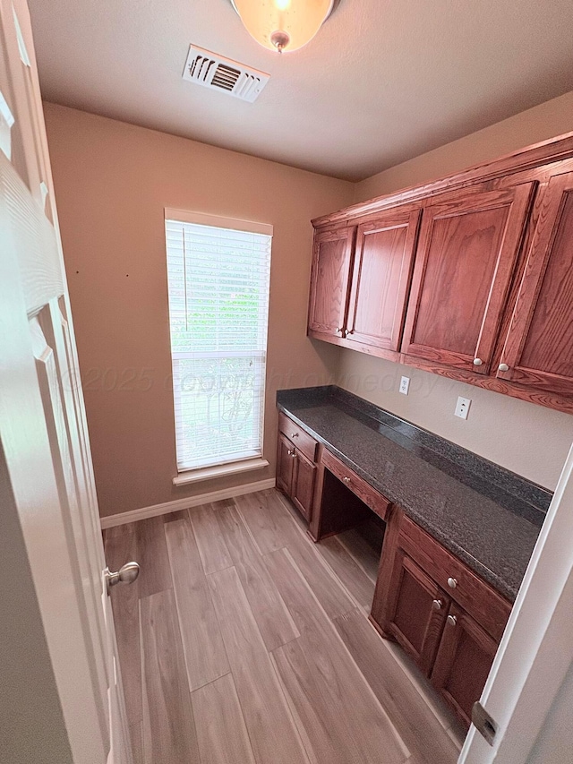 9317 Shylana Ave, Amarillo, TX 79119 - unfurnished office featuring light wood-type flooring, built in desk, and baseboards