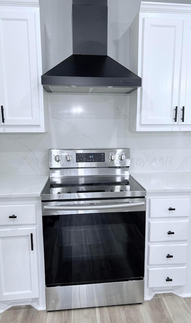 9317 Shylana Ave, Amarillo, TX 79119 - kitchen with electric stove, wall chimney exhaust hood, white cabinetry, light wood-type flooring, and light stone countertops