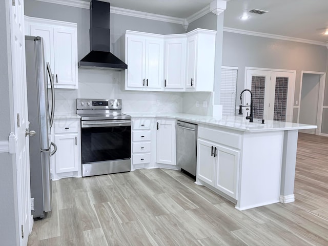 9317 Shylana Ave, Amarillo, TX 79119 - kitchen with stainless steel appliances, wall chimney range hood, a peninsula, light wood-style floors, and ornamental molding