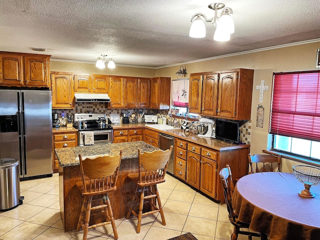 kitchen featuring stainless steel appliances, a notable chandelier, backsplash, crown molding, and a kitchen island