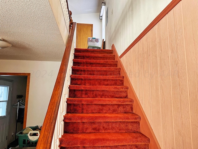 stairs with wood walls and lofted ceiling