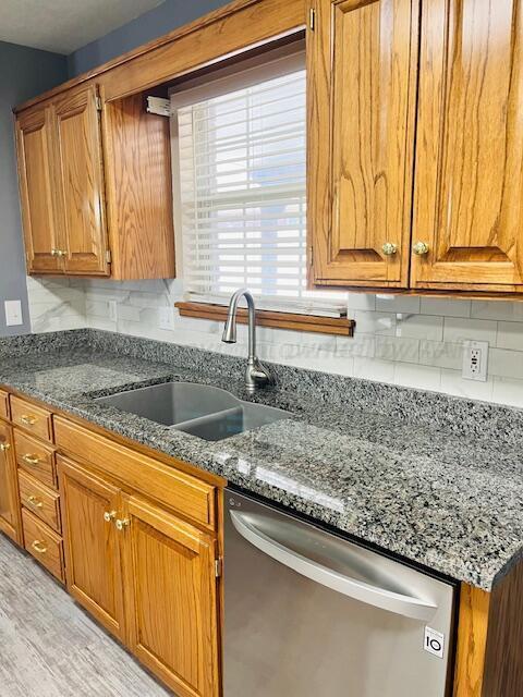 kitchen featuring a sink, decorative backsplash, brown cabinets, and dishwasher