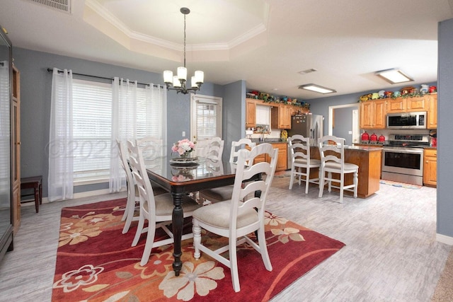 dining room with a tray ceiling, plenty of natural light, a notable chandelier, and crown molding