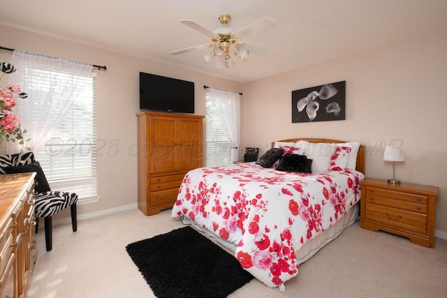 bedroom featuring light colored carpet, a ceiling fan, and baseboards