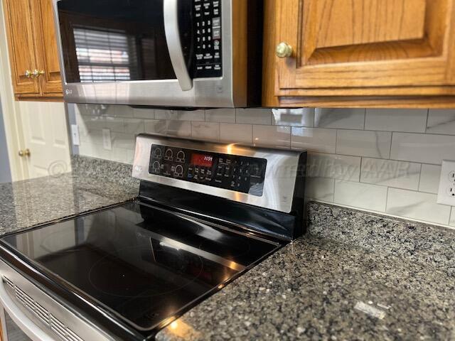 details with dark stone countertops, brown cabinets, and stainless steel appliances