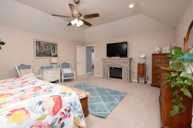 carpeted bedroom with baseboards, ceiling fan, vaulted ceiling, a glass covered fireplace, and a raised ceiling